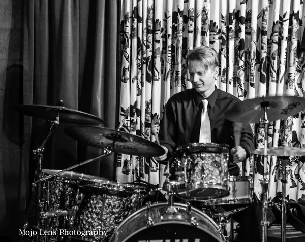 Chad Eisinger playing drums on stage in black and white