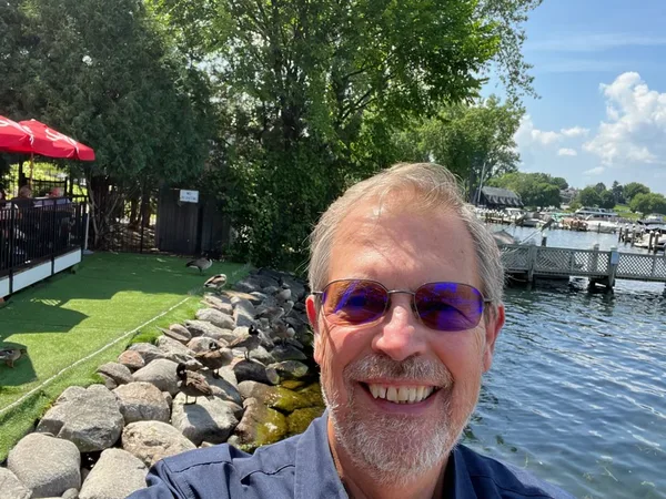 Tim D. Binegar at a marina with geese along the rocky shore