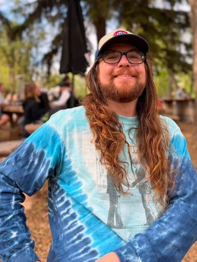 Sean smiling outdoors in a tie-dye shirt and baseball cap